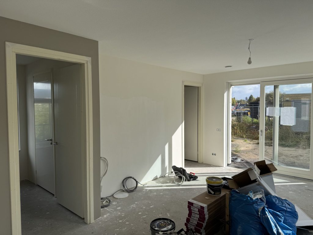 Woonkamer tijdens de afwerking, met emmers, dozen en een openslaande tuindeur