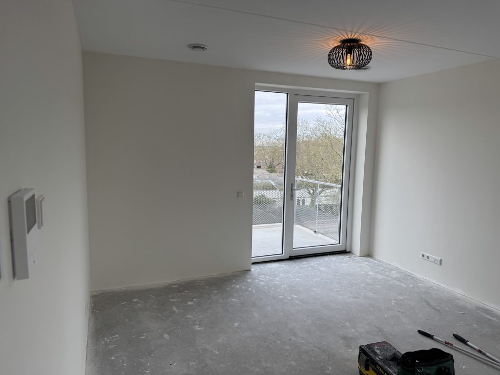 Lege kamer met strakke witte wanden en een deur naar het balkon